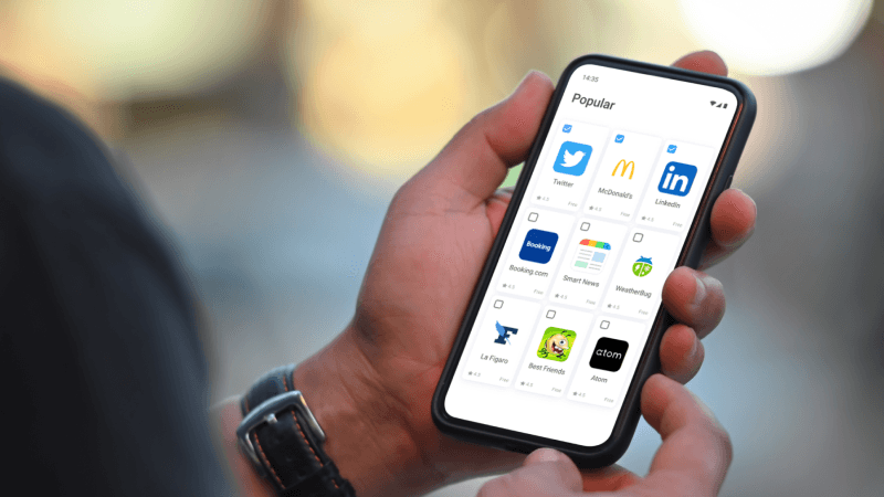 Человек с телефоном, на экране которого отображаются приложения
